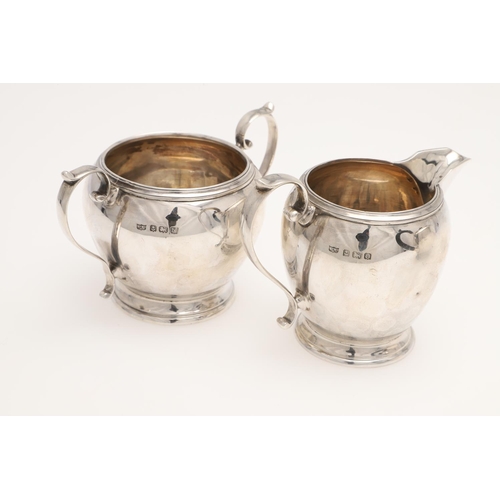 111 - A 20TH CENTURY THREE-PIECE SILVER TEA SET. circular form, with incised borders and scroll handles, b... 