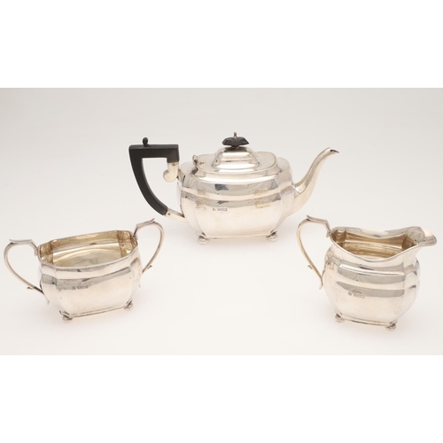 120 - A GEORGE V THREE-PIECE SILVER TEA SET. shaped rectangular form, with angular handles and on bun feet... 