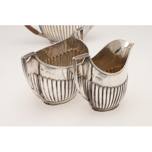 126 - A LATE VICTORIAN THREE-PIECE SILVER TEA SET. of oval outline, with angular handles and part-fluted b... 