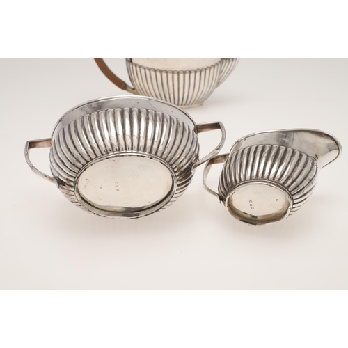 126 - A LATE VICTORIAN THREE-PIECE SILVER TEA SET. of oval outline, with angular handles and part-fluted b... 