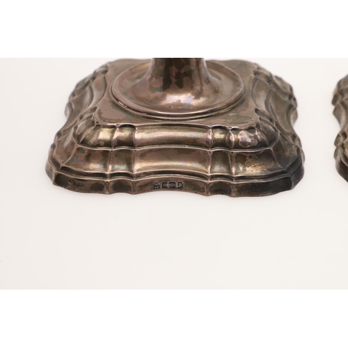 153 - A PAIR OF EDWARDIAN SILVER CANDLESTICKS. with spool-shaped capitals, detachable nozzles, knopped ste... 