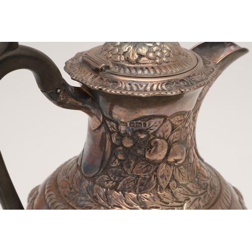 158 - AN EDWARDIAN SILVER HOT WATER JUG. circular form, with a scroll handle and the whole profusely embos... 