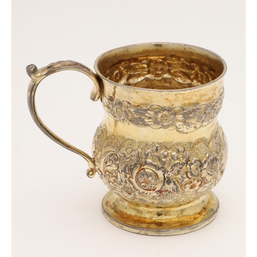 169 - A GEORGE III IRISH SILVERGILT MUG. of campana form, with a scroll handle and the body chased & embos... 