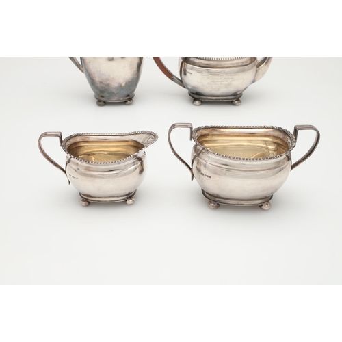 68 - A GEORGE V FOUR-PIECE SILVER TEA SET. with oblong bodies, husk & scroll corners, and raised on bun f... 