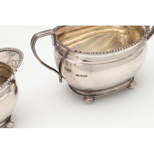 68 - A GEORGE V FOUR-PIECE SILVER TEA SET. with oblong bodies, husk & scroll corners, and raised on bun f... 