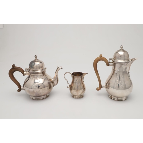 69 - A GEORGE V THREE-PIECE SILVER TEA SET. of baluster form, with scroll handles, on spreading circular ... 