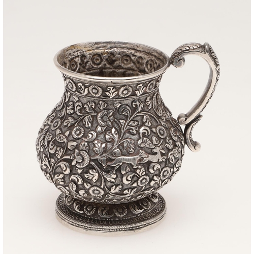 99 - A LATE 19TH CENTURY INDIAN SILVER MUG. of baluster form, profusely chased & embossed with foliage an... 