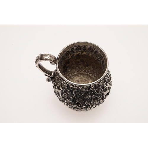 99 - A LATE 19TH CENTURY INDIAN SILVER MUG. of baluster form, profusely chased & embossed with foliage an... 