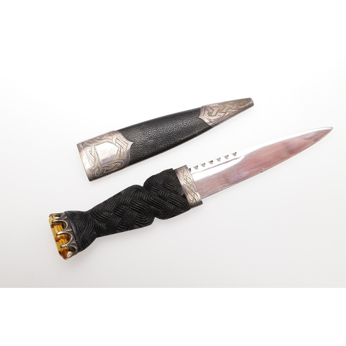 139 - A SCOTTISH SILVER MOUNTED SGIAN-DUBH. With a 9 cm Stainless Steel blade on a carved interlaced grip ... 