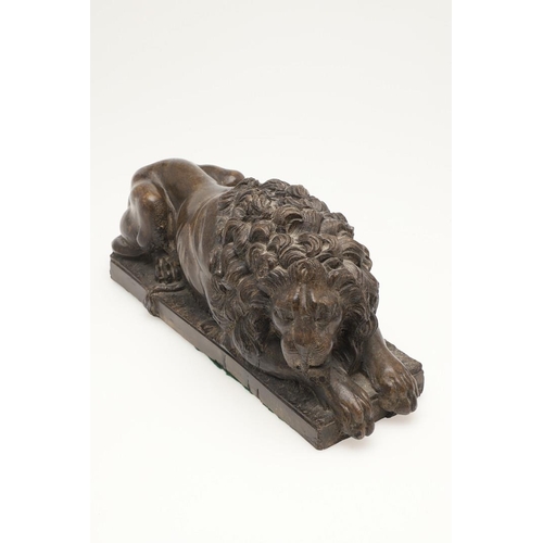 419 - A 20TH CENTURY SCULPTURE OF A RECUMBENT LION. with bronze effect finish, upon a rectangular base, un... 