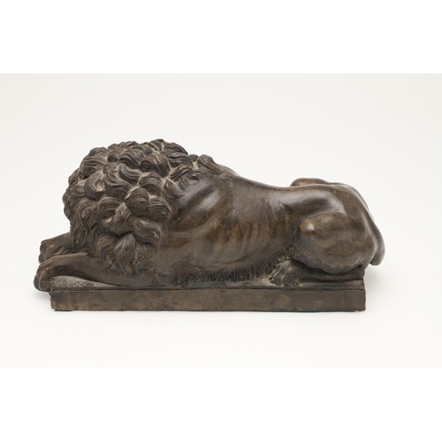 419 - A 20TH CENTURY SCULPTURE OF A RECUMBENT LION. with bronze effect finish, upon a rectangular base, un... 