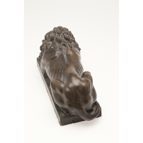 419 - A 20TH CENTURY SCULPTURE OF A RECUMBENT LION. with bronze effect finish, upon a rectangular base, un... 