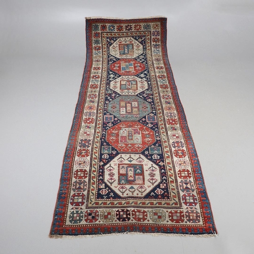 509 - A CAUCASIAN RUNNER, CIRCA 1900. the indigo field with a column of octagons containing stylised plant... 