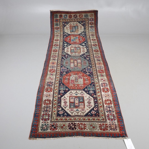 509 - A CAUCASIAN RUNNER, CIRCA 1900. the indigo field with a column of octagons containing stylised plant... 