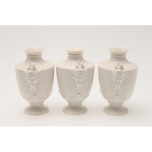 593 - NYPHENBURG - SET OF SATYR MINIATURE URNS. A set of 8 miniature urns in the white, of tapering shape ... 