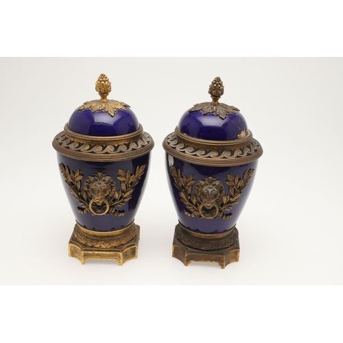 610 - PAIR OF SEVRES STYLE LIDDED PORCELAIN URNS. A pair of porcelain and gilded metal mounted urns,  with... 