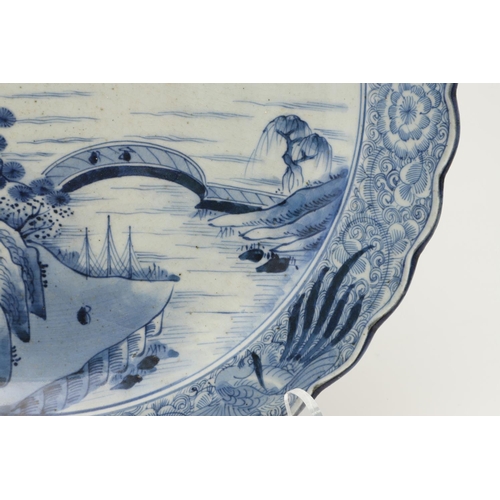 624 - LARGE JAPANESE ARITA DISH. A large blue and white Arita dish, painted with a bridge within a landsca... 