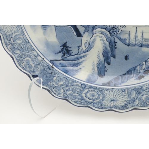 624 - LARGE JAPANESE ARITA DISH. A large blue and white Arita dish, painted with a bridge within a landsca... 