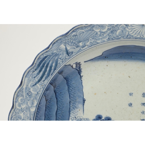 624 - LARGE JAPANESE ARITA DISH. A large blue and white Arita dish, painted with a bridge within a landsca... 