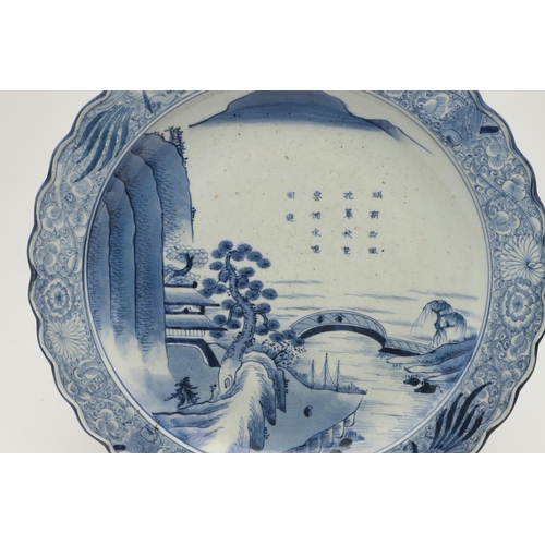 624 - LARGE JAPANESE ARITA DISH. A large blue and white Arita dish, painted with a bridge within a landsca... 