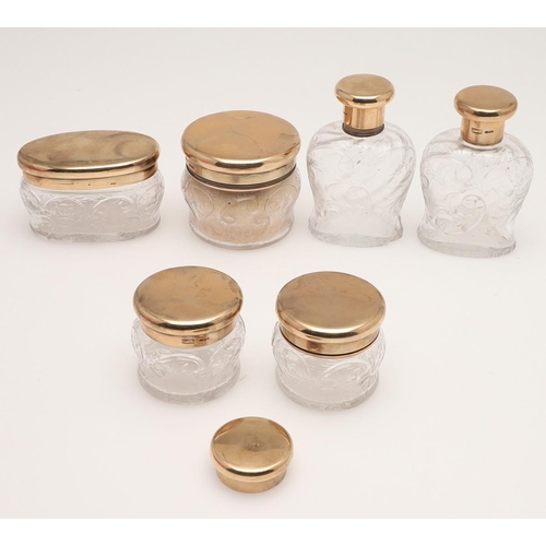 103 - A GEORGE V SUITE OF SIX 9CT. GOLD MOUNTED CUT-GLASS DRESSING TABLE BOTTLES & JARS. including an oval... 