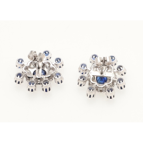 214 - A PAIR OF SAPPHIRE AND DIAMOND CLUSTER EARRINGS. each earring centred with an oval-shaped sapphire w... 