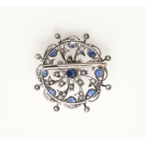 215 - A SAPPHIRE AND DIAMOND BROOCH PENDANT. of circular foliate form, set with circular-cut sapphires and... 