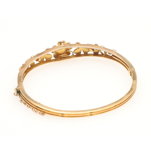 251 - AN ANTIQUE GOLD AND PEARL HALF HINGED BANGLE. mounted to one side with foliate decoration set with h... 