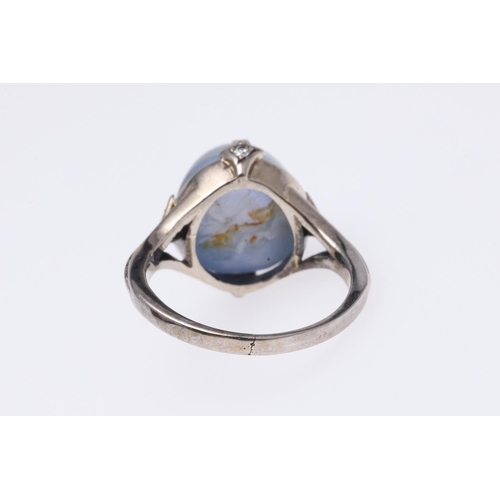 267 - A STAR SAPPHIRE AND DIAMOND RING. the cabochon sapphire is set with four circular-cut diamonds in wh... 