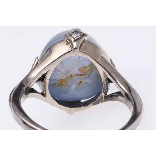 267 - A STAR SAPPHIRE AND DIAMOND RING. the cabochon sapphire is set with four circular-cut diamonds in wh... 