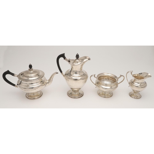 47 - A GEORGE V FOUR-PIECE SILVER TEA SET. of circular form, with scroll handle, decorated around the low... 