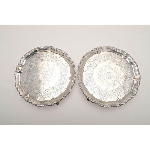 62 - A PAIR OF GEORGE III SMALL SILVER SALVERS OR WAITERS. of shaped circular outline, with gadrooned bor... 