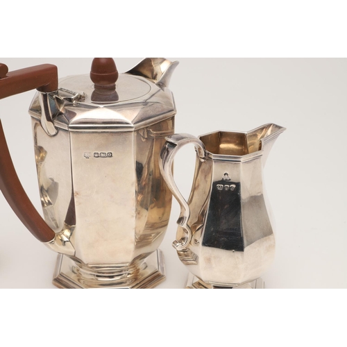 63 - A GEORGE V SILVER HOT WATER JUG. of octagonal form, with an angular handle and an acorn finial, by H... 