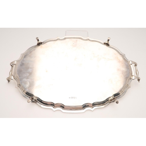 64 - A GEORGE V SILVER TWO-HANDLED TRAY. of shaped oval outline, with a moulded border and raised on hoof... 