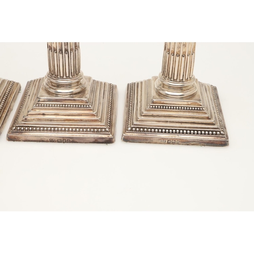 65 - TWO PAIRS OF LATE VICTORIAN SILVER CANDLESTICKS. with bead borders, fluted columns and on stepped sq... 