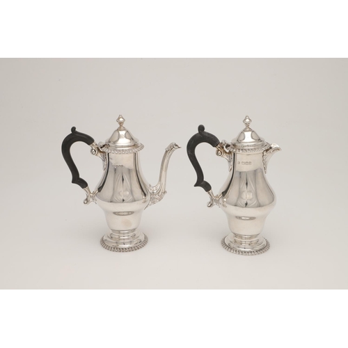 83 - A PAIR OF GEORGE V SILVER CAFE AU LAIT POTS. with bellied bodies, textured borders, 'S'-scroll handl... 