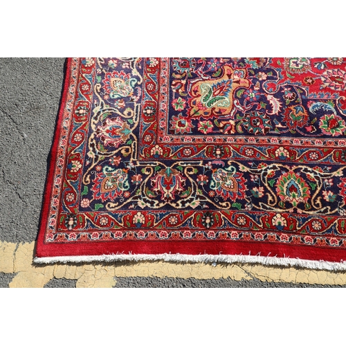 A KASHAN CARPET. The raspberry field of scrolling vines centred by a ...