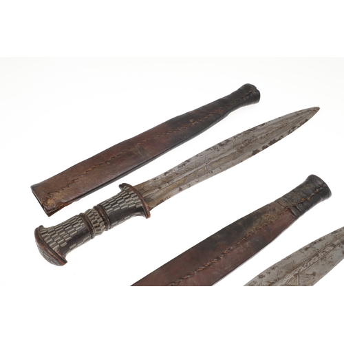 108 - A NEAR IDENTICAL PAIR OF SUDANESE KNIVES AND SCABBARDS. The two blades 32 cm and 30 cm, with curved ... 