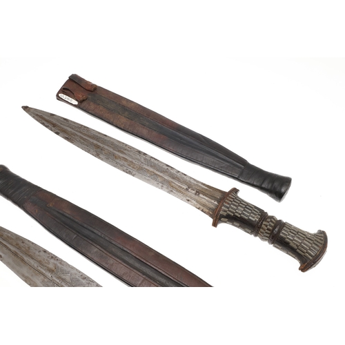 108 - A NEAR IDENTICAL PAIR OF SUDANESE KNIVES AND SCABBARDS. The two blades 32 cm and 30 cm, with curved ... 