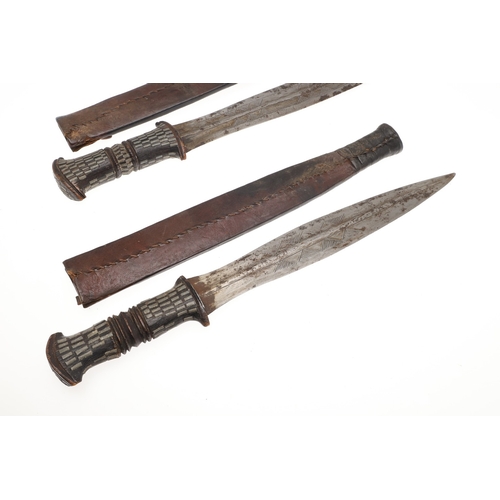 108 - A NEAR IDENTICAL PAIR OF SUDANESE KNIVES AND SCABBARDS. The two blades 32 cm and 30 cm, with curved ... 