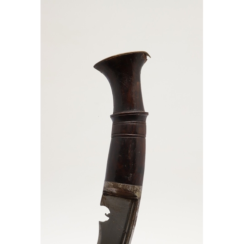 69 - A KUKRI KNIFE AND SCABBARD. With a traditionally shaped 25 cm pointed blade on a hardwood handle. In... 