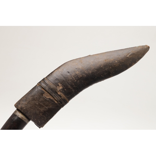 69 - A KUKRI KNIFE AND SCABBARD. With a traditionally shaped 25 cm pointed blade on a hardwood handle. In... 
