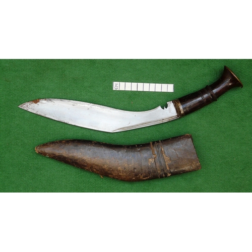 69 - A KUKRI KNIFE AND SCABBARD. With a traditionally shaped 25 cm pointed blade on a hardwood handle. In... 