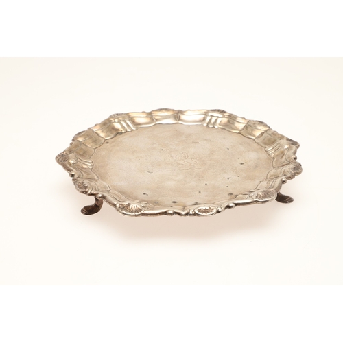 21 - A GEORGE II SILVER WAITER. Of shaped rounded form with shell motif decoration to the border, on thre... 