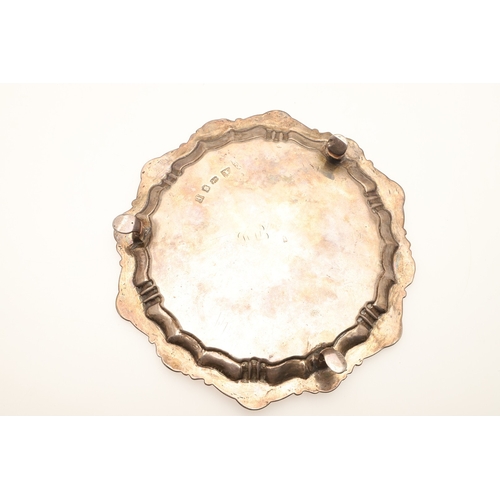 21 - A GEORGE II SILVER WAITER. Of shaped rounded form with shell motif decoration to the border, on thre... 