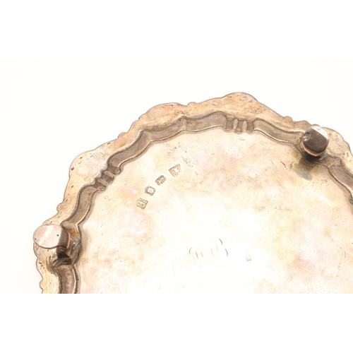 21 - A GEORGE II SILVER WAITER. Of shaped rounded form with shell motif decoration to the border, on thre... 