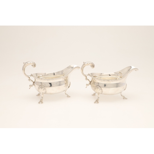 26 - A PAIR OF GEORGE III SILVER SAUCE BOATS. Each one featuring a heavy gadrooned border and scroll hand... 