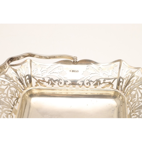 37 - AN EDWARDIAN SILVER BASKET. With pierced foliate design sides and to the movable handle, raised on f... 