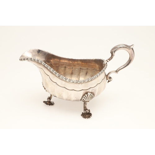 43 - AN EARLY GEORGE III SILVER SAUCE BOAT. With gadrooned border and scalloped edge faceted body, scroll... 