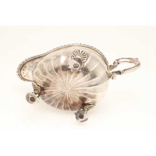 43 - AN EARLY GEORGE III SILVER SAUCE BOAT. With gadrooned border and scalloped edge faceted body, scroll... 